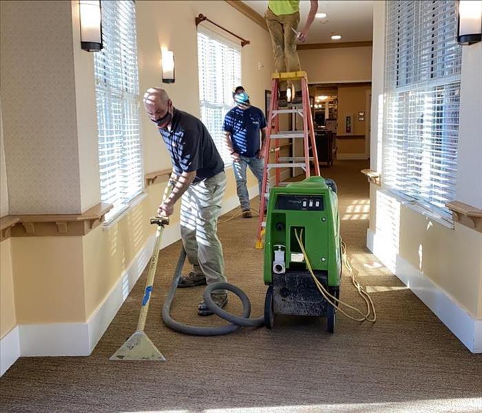 SERVPRO team members are removing water from a carpet.