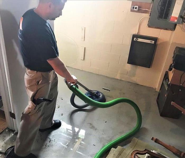 servpro employee using a portable extractor in concrete basement