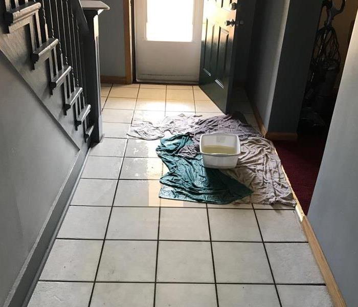 bucket of water on tile floor with wet towels and visible water surrounding the area