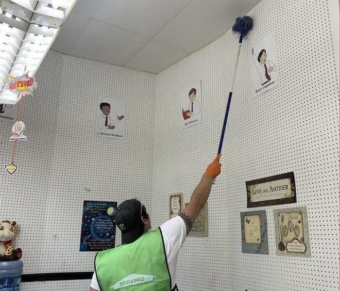 SERVPRO employee with duster cleaning the ceiling and walls of a classroom